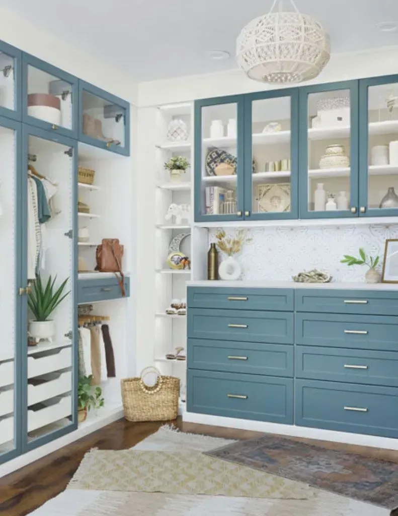 A walk in closet with blue cabinets and glass doors.