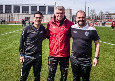 Three men pose on a soccer field. 