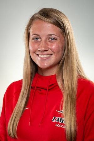 Woman smiling, wearing a red sweatshirt, blonde hair, against a gray background.