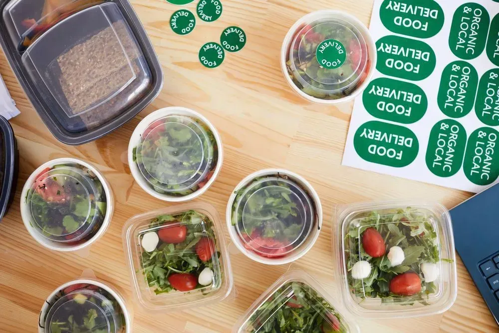 A Wooden Table Topped With Bowls of Food and Stickers That Say Food Delivery — Aldine Printers in Bungalow, QLD