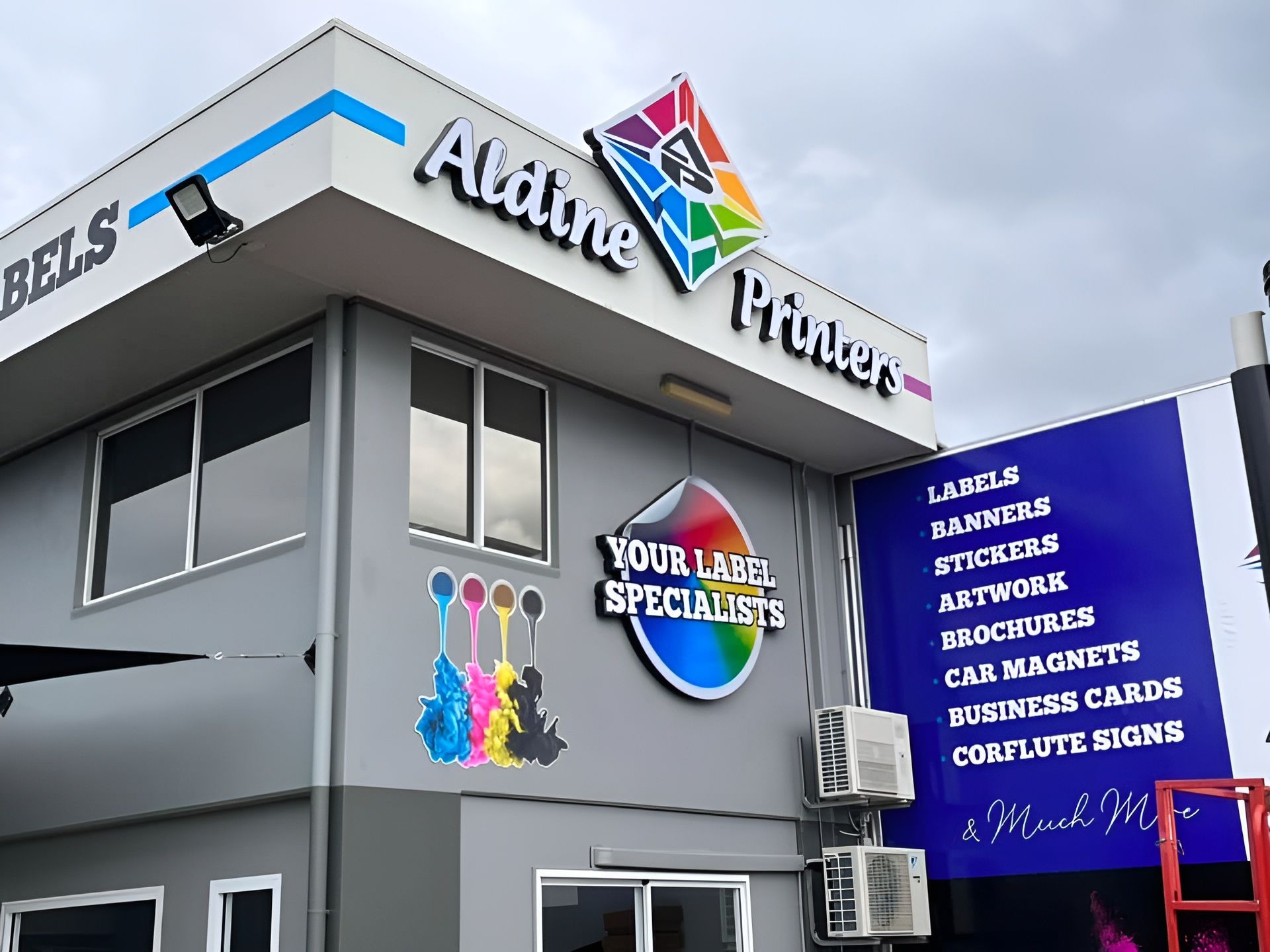 Modern storefront showcasing Custom Stickers Cairns with colourful signage on a grey corner building