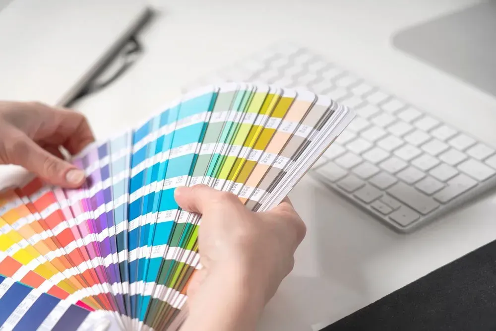 A person is holding a palette of colors in front of a keyboard — Aldine Printers in Bungalow, QLD