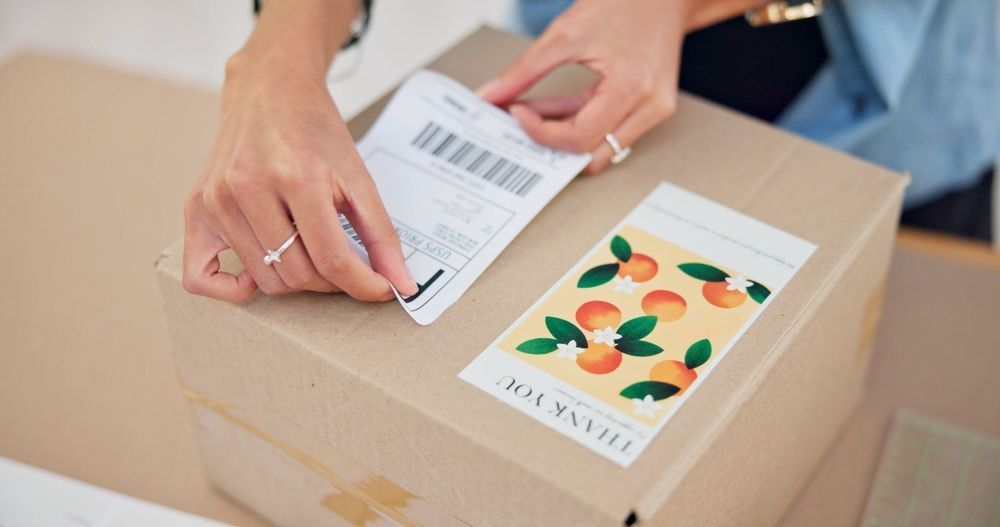 A Person is Putting a Sticker on a Cardboard Box — Aldine Printers in Bungalow, QLD