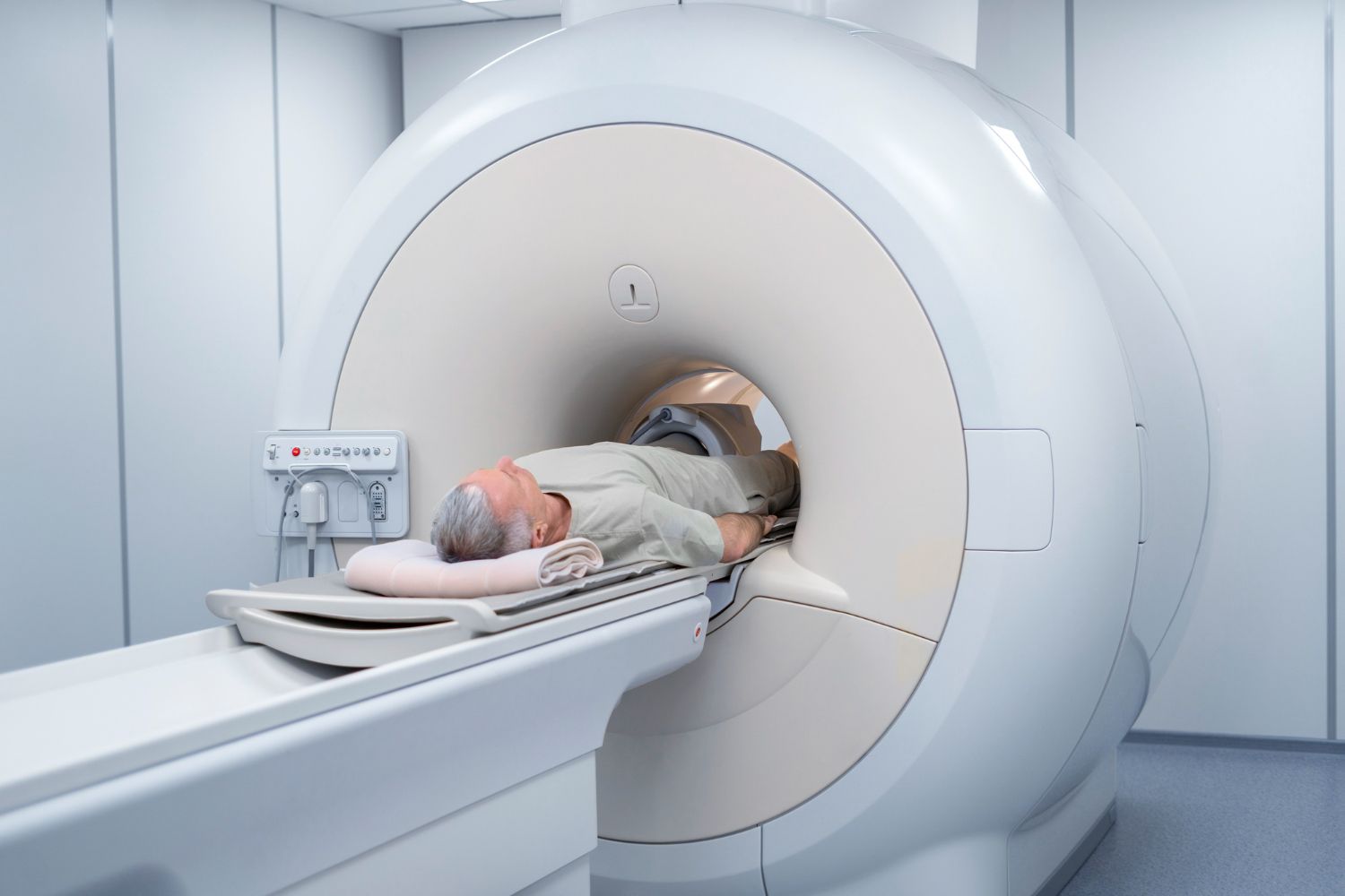 Man lying face down in an MRI machine for a medical scan in a sterile room.