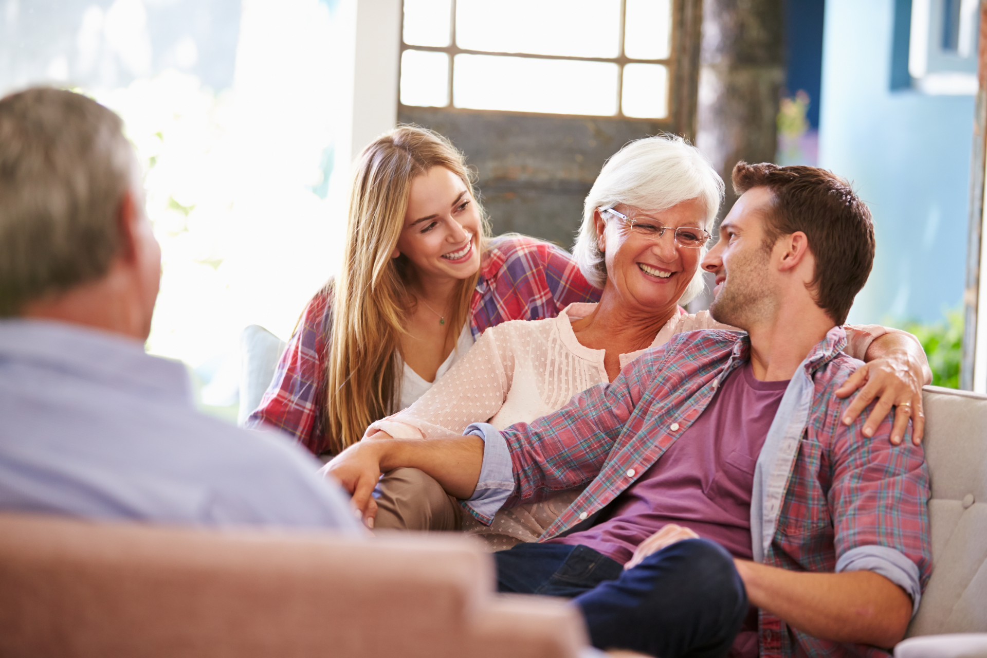 Family sitting on couch, smiling and talking. Mom hugs her daughter and son.