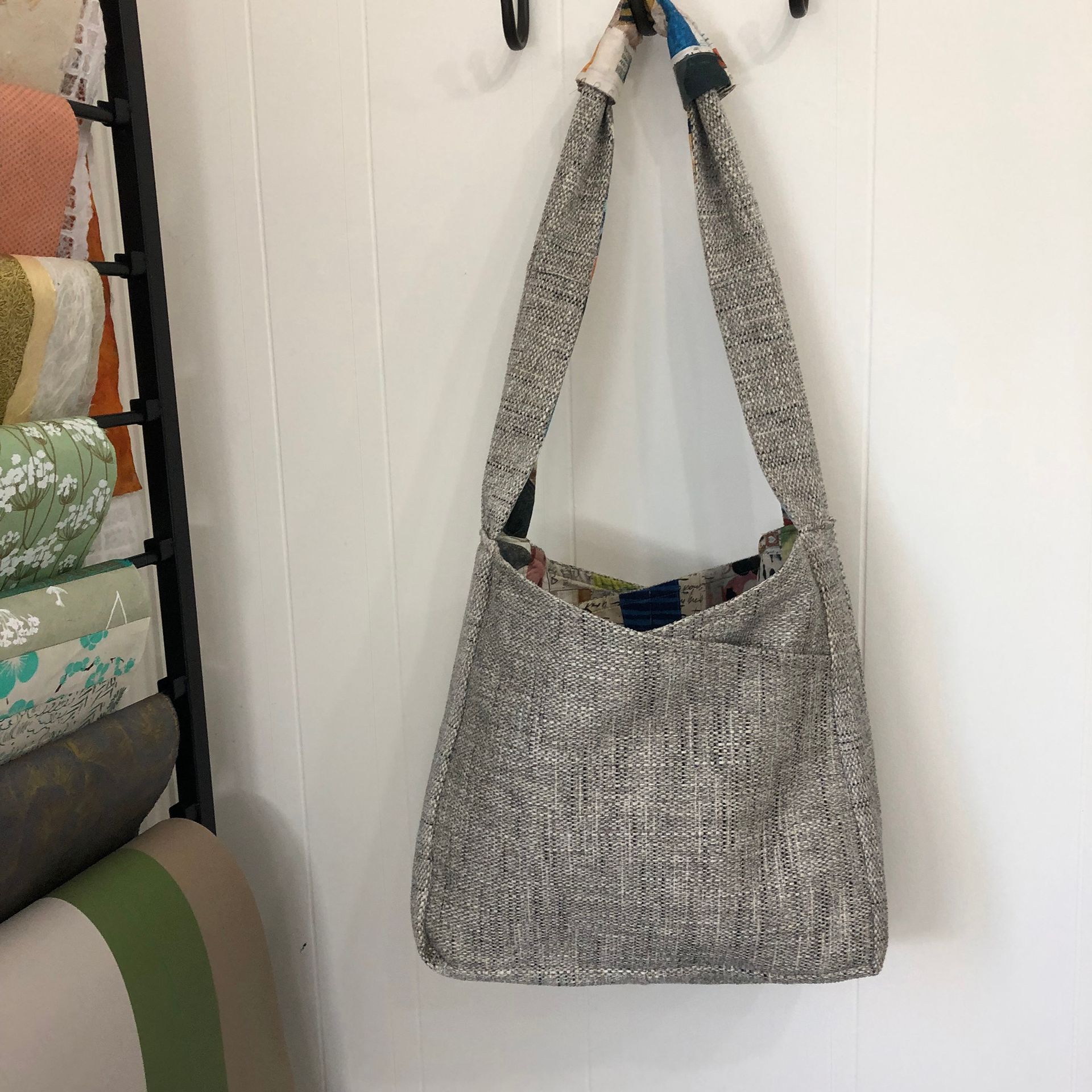 Hanging woven fabric shoulder bag, silver and gray, with colorful accents.