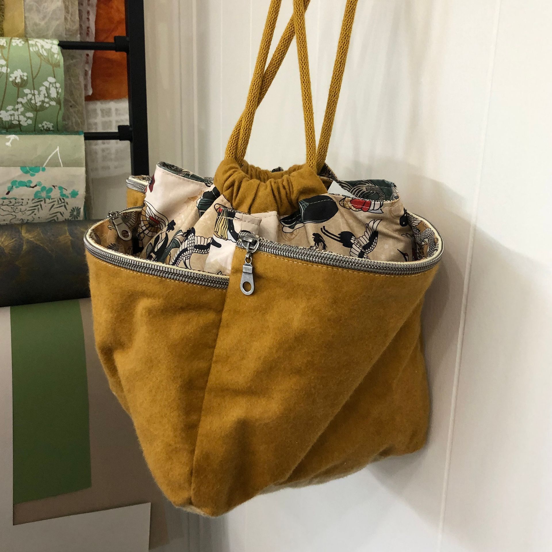 Yellow drawstring pouch with a patterned lining, sitting on a patterned white bedspread.