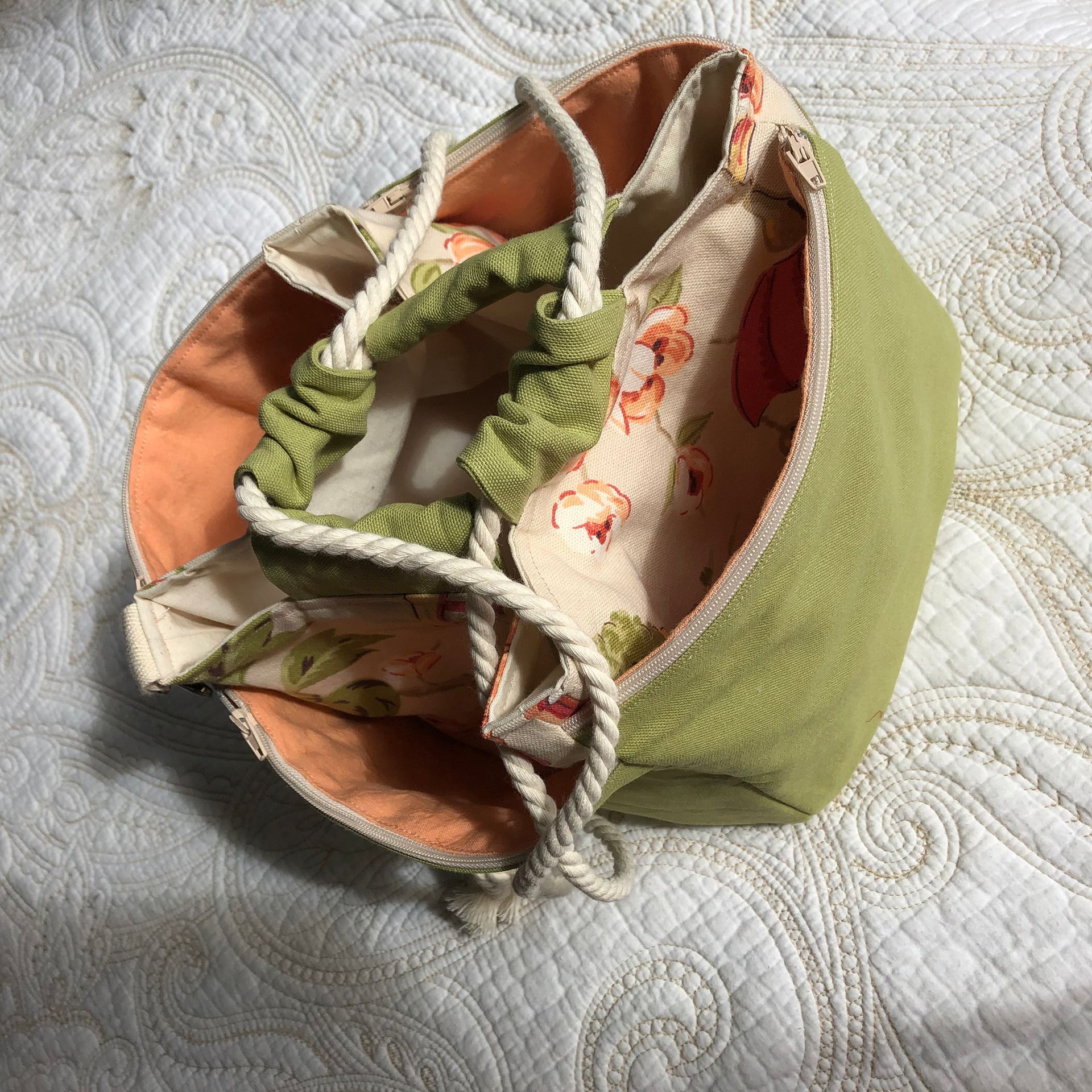 Green and floral fabric drawstring bag open, sitting on a patterned white surface.