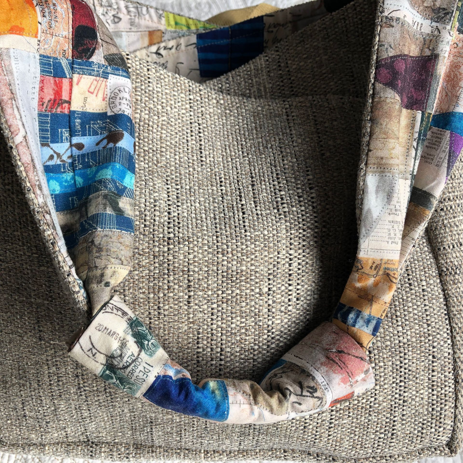 Hanging woven fabric shoulder bag, silver and gray, with colorful accents.