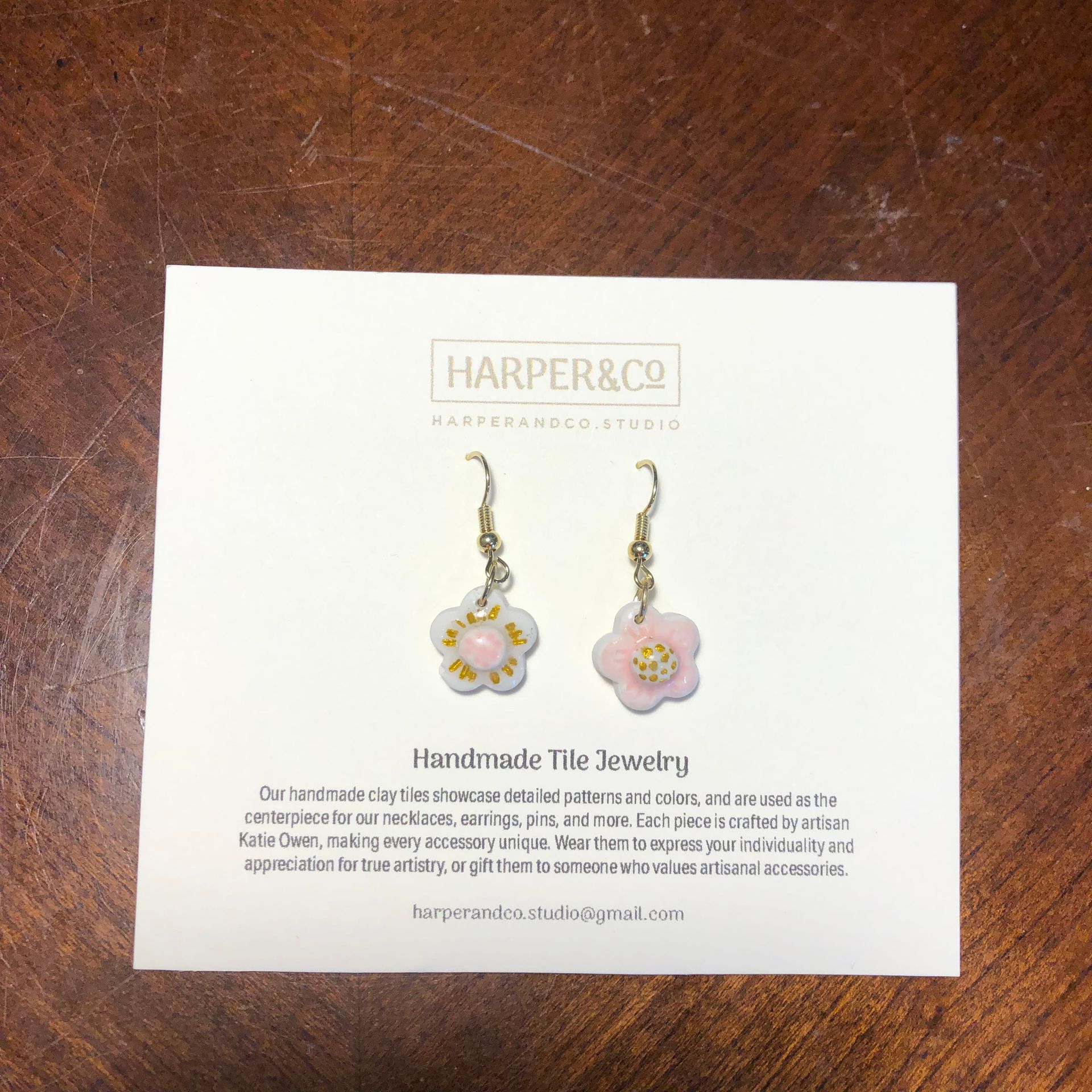 Pink flower earrings on a white card with branding.