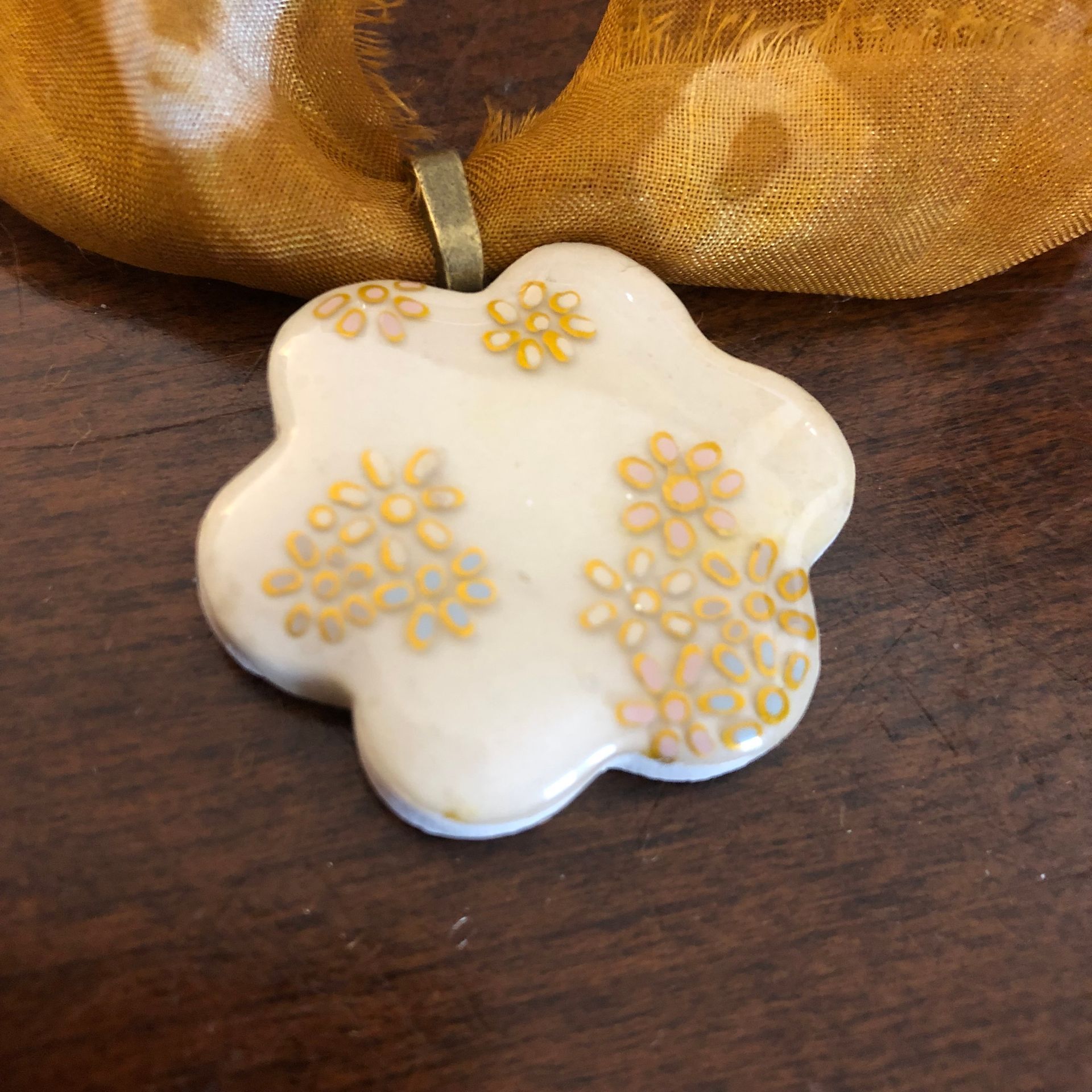 Mustard and green patterned scarf necklace with a flower pendant.