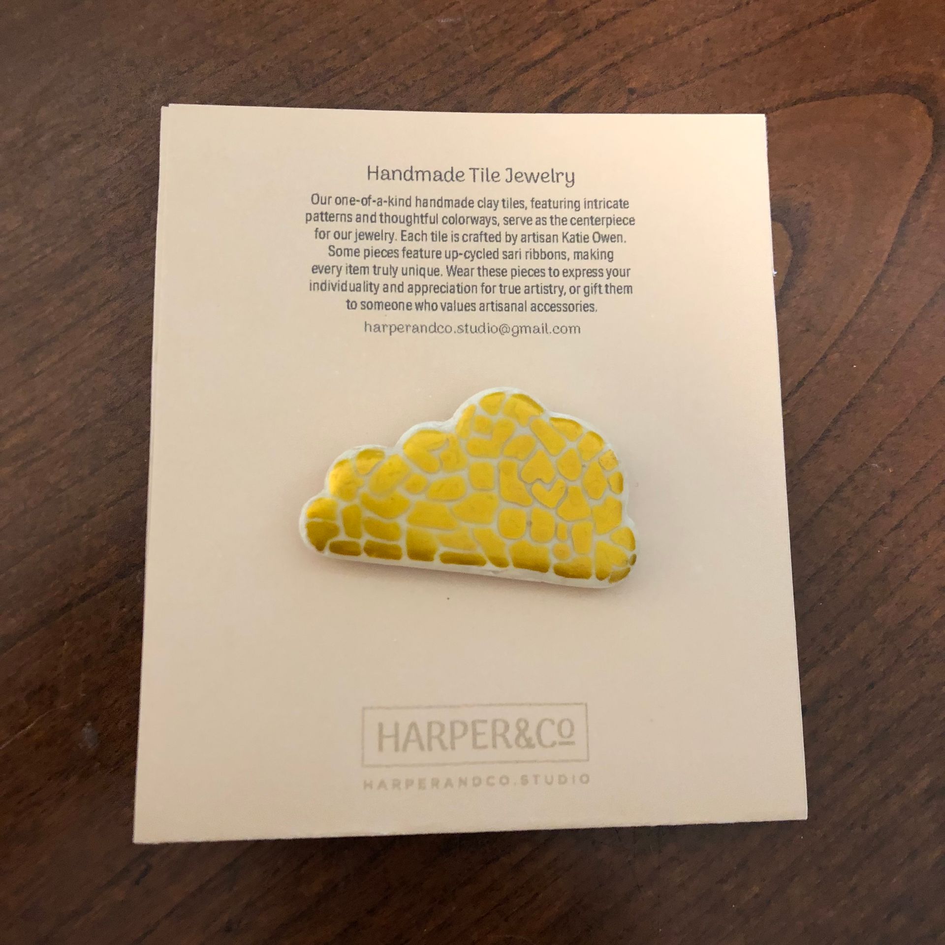 Cloud-shaped yellow enamel pin on a white card with text,