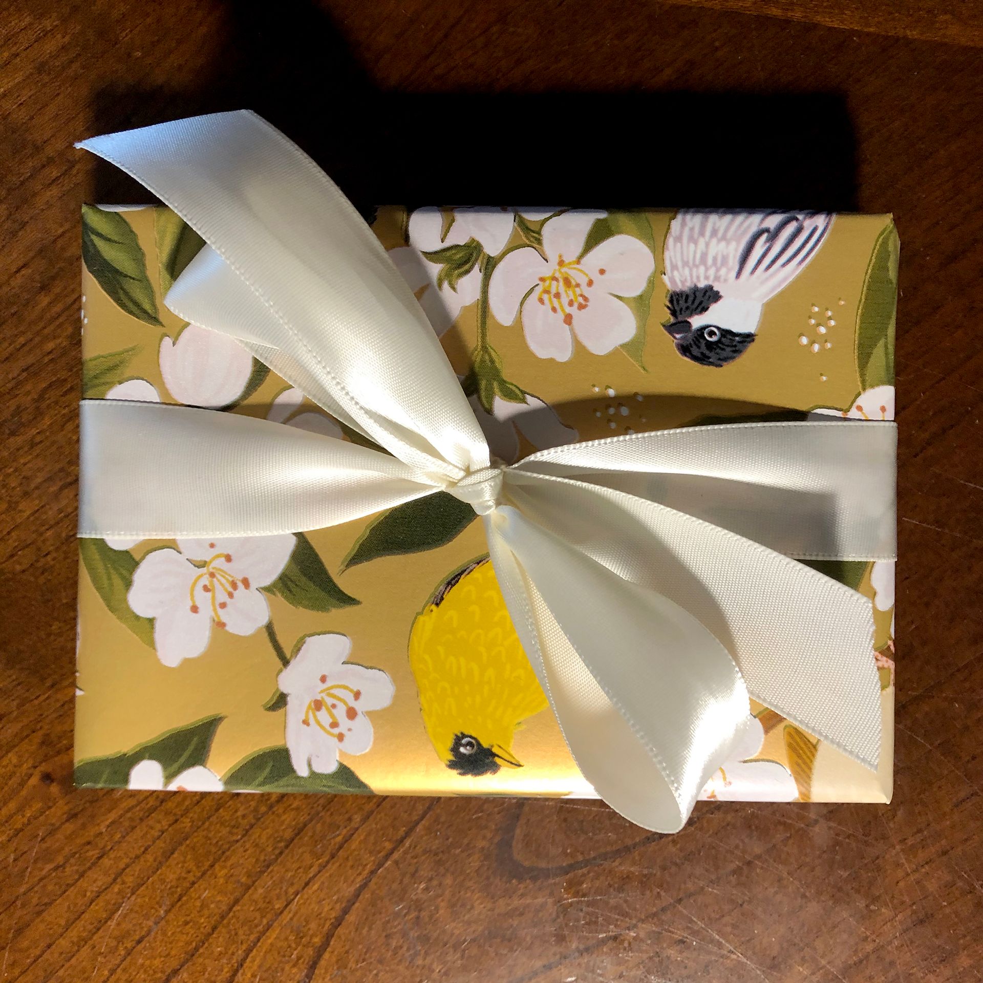 Gift wrapped in yellow floral paper with white bow.