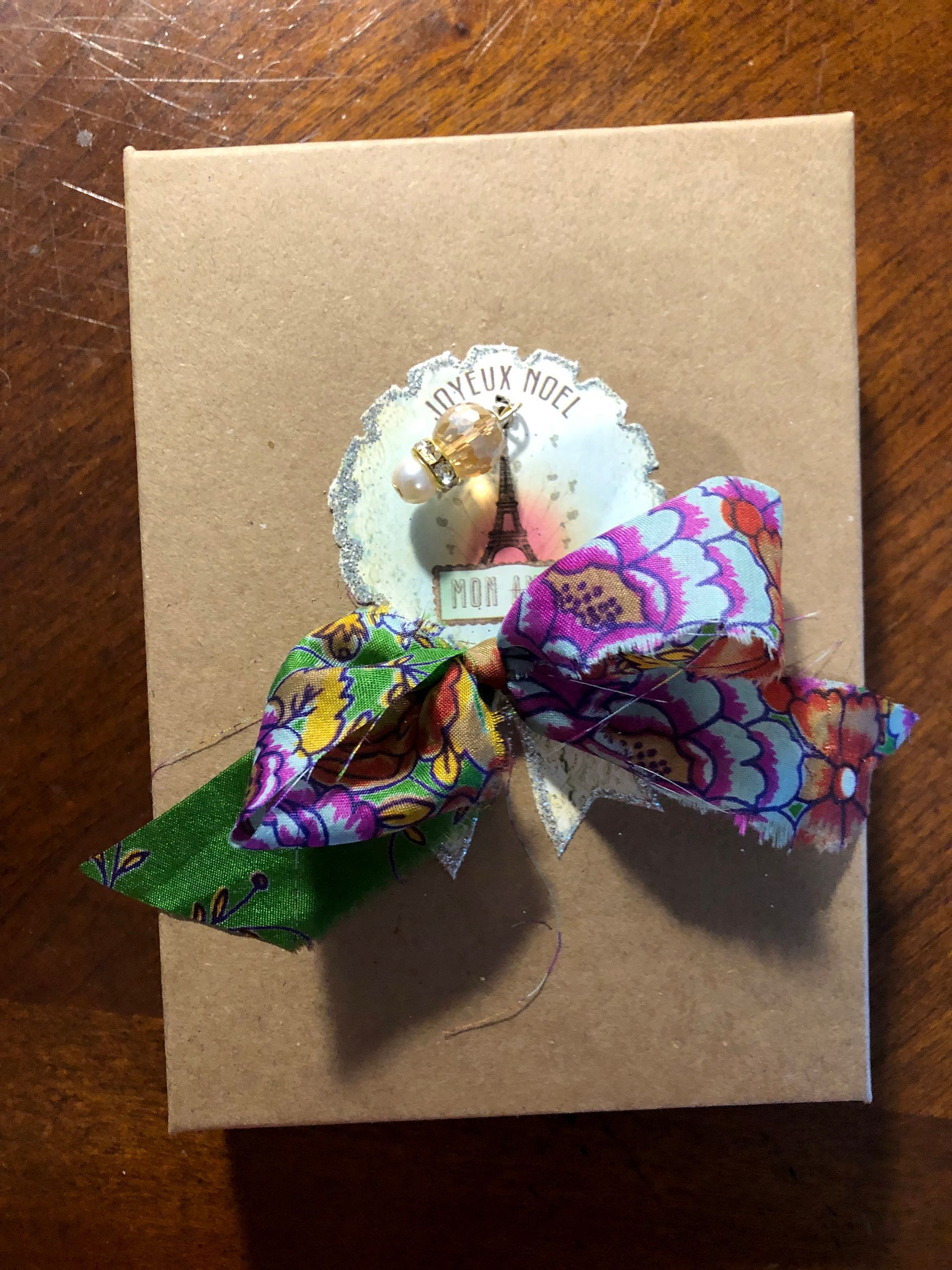 Gift box with floral ribbon bow and decorative sticker.