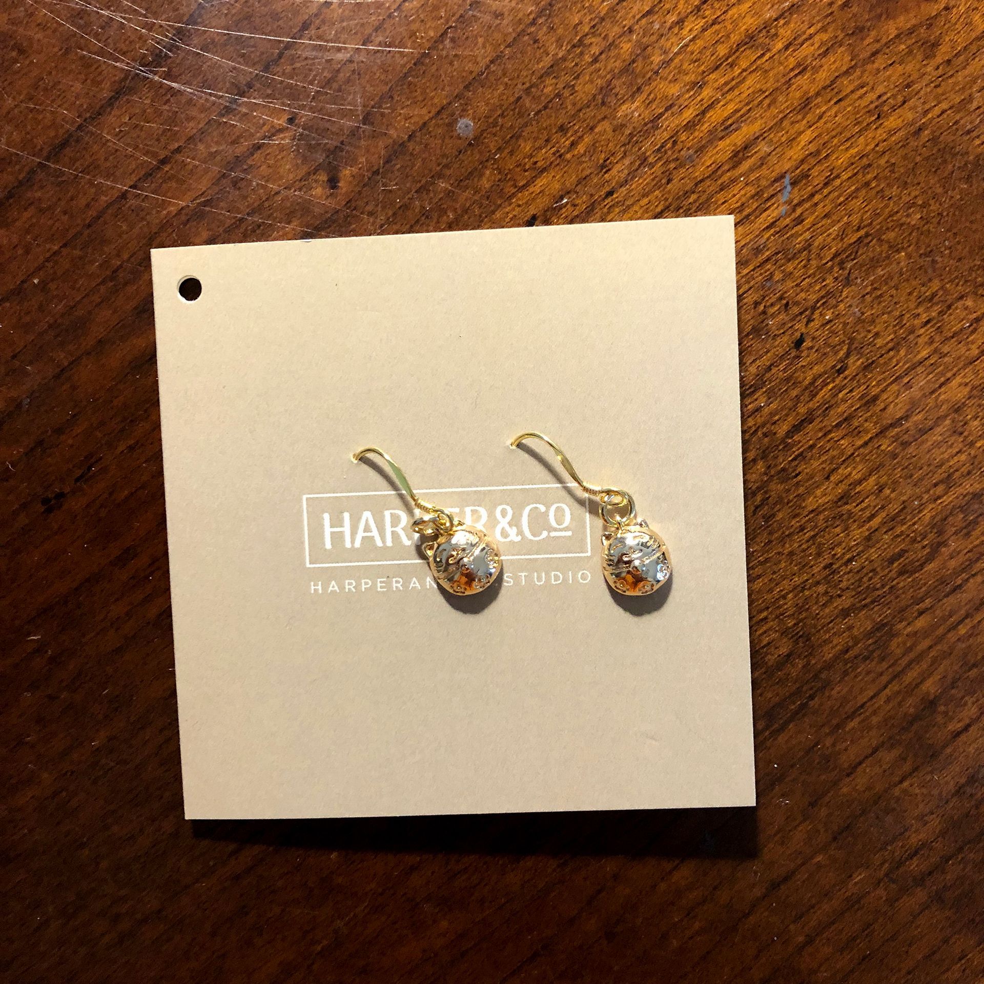 Pair of gold earrings on a light tan card with