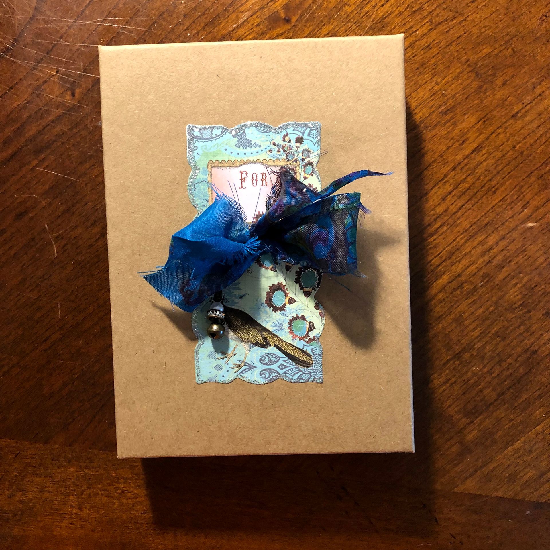 Cardboard box with blue ribbon and patterned paper embellishments.