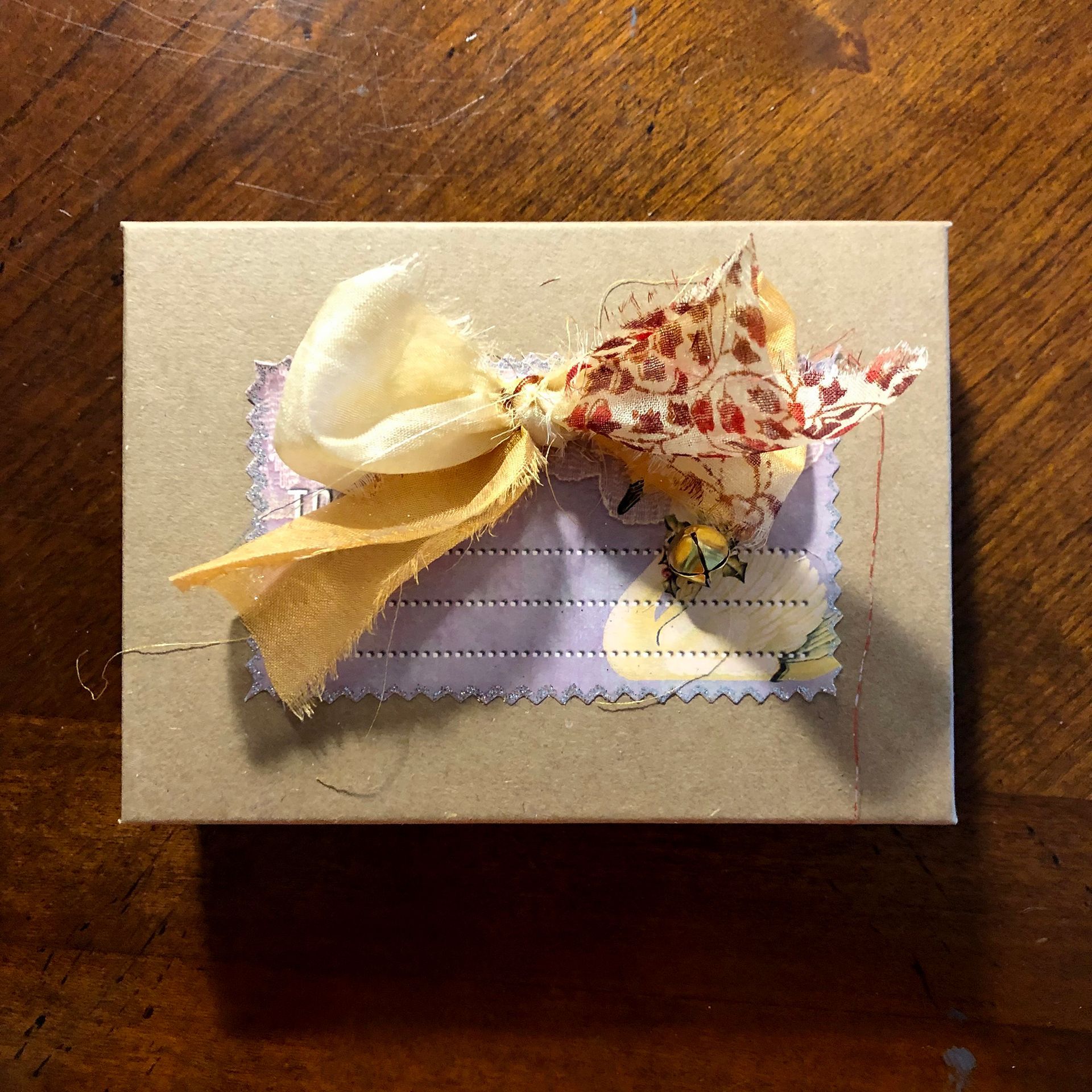 Gift box with a fabric bow and a small, stitched-on tag.