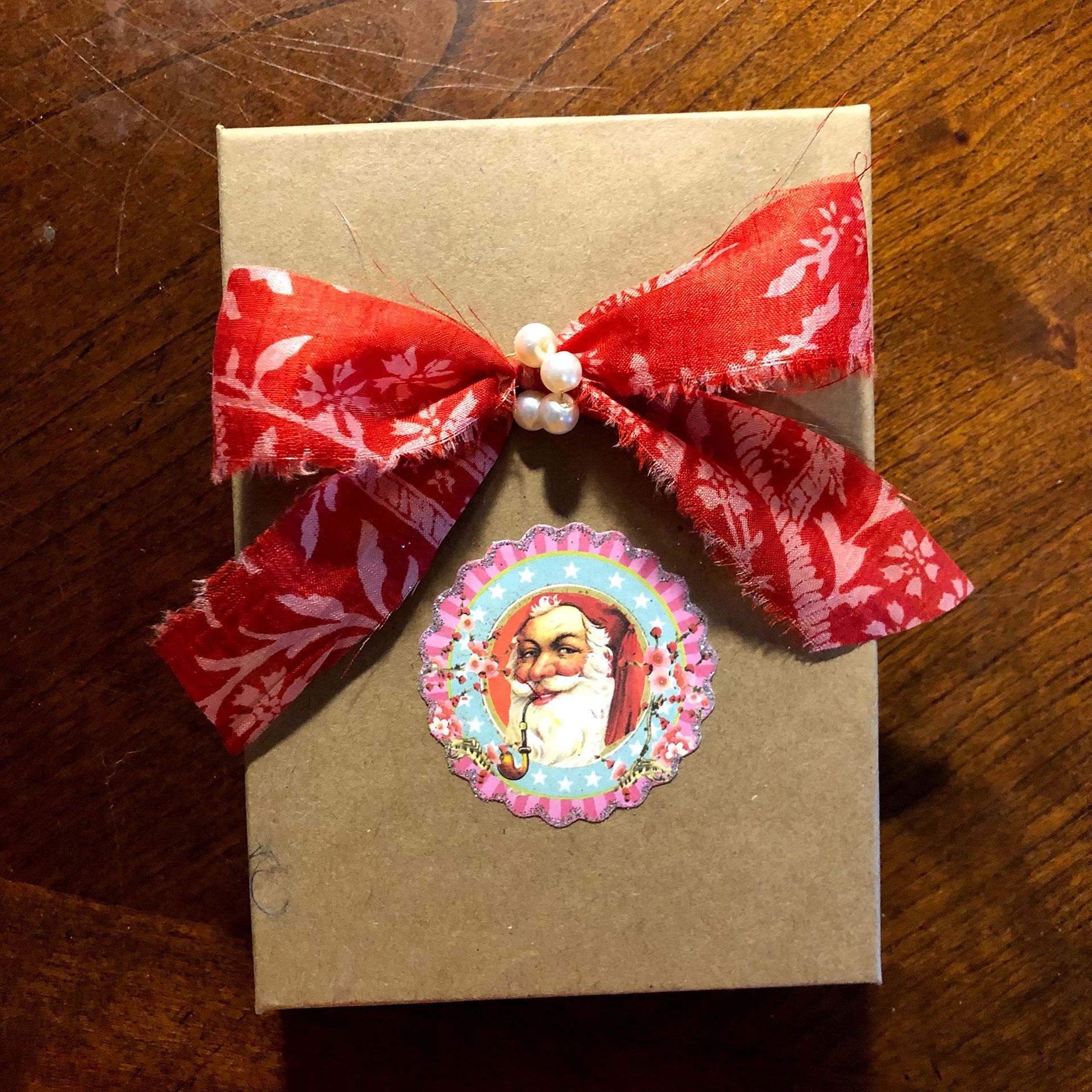 Gift box with red floral ribbon bow and Santa sticker.