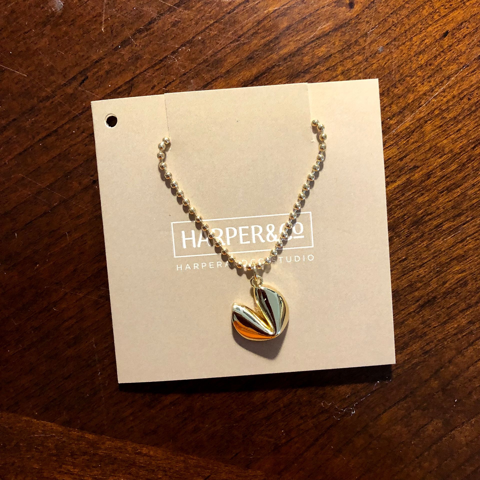 Gold heart pendant necklace on a tan card, Harper & Co. logo.