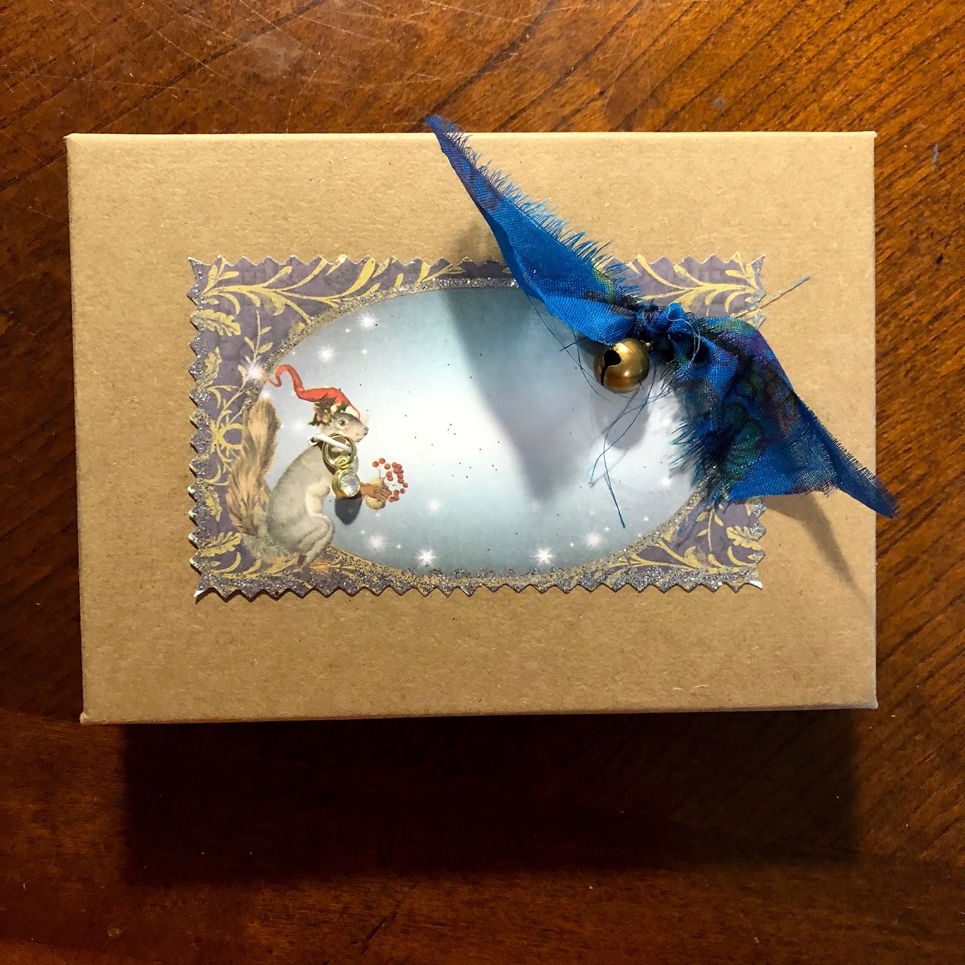 Cardboard gift box with a squirrel illustration and blue ribbon embellishment.