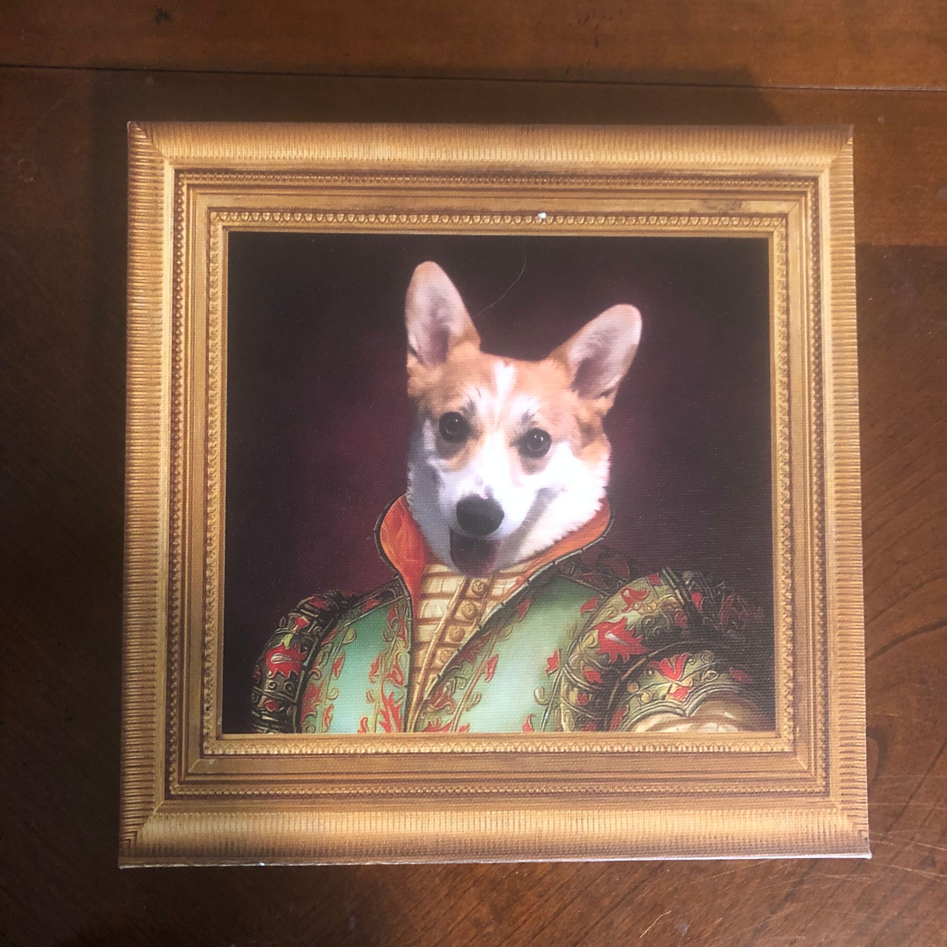 Corgi portrait in gilded frame, wearing Renaissance attire; red and green with dark red background.