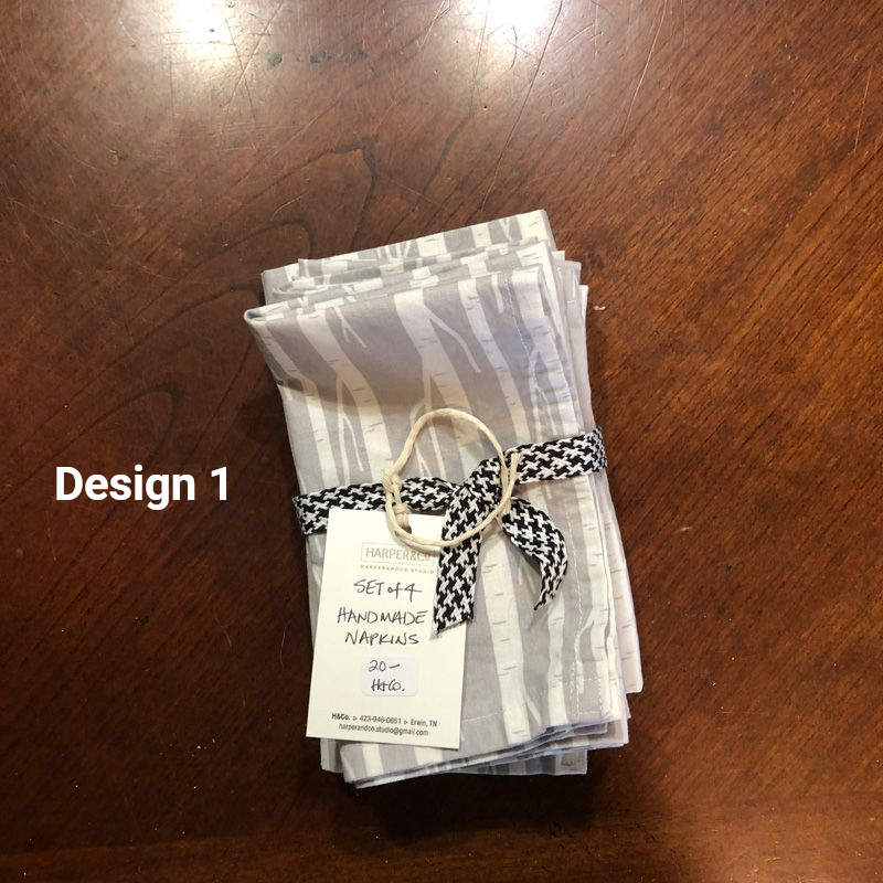 A set of four grey and white patterned handmade napkins tied with a black and white ribbon and a price tag.