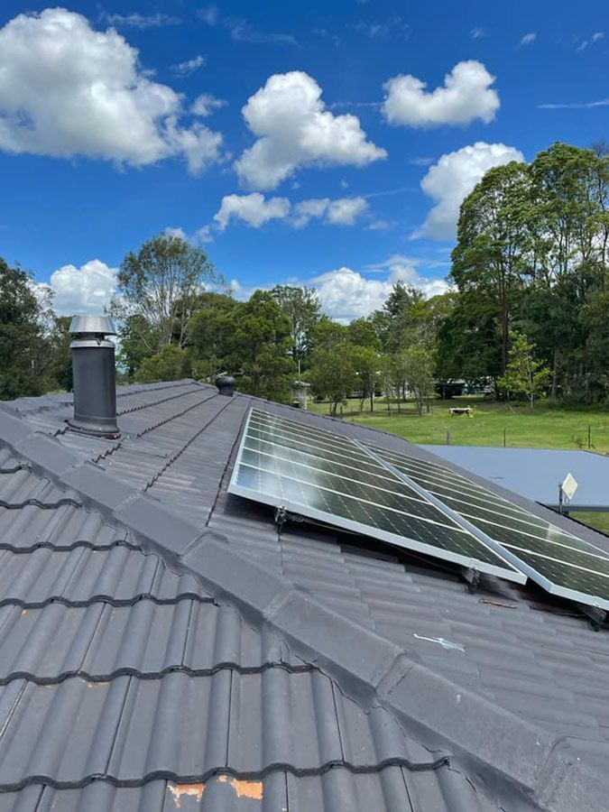 A Roof With a Chimney and Solar Panels on It — Ben McLennan Constructions in Glen Innes, NSW