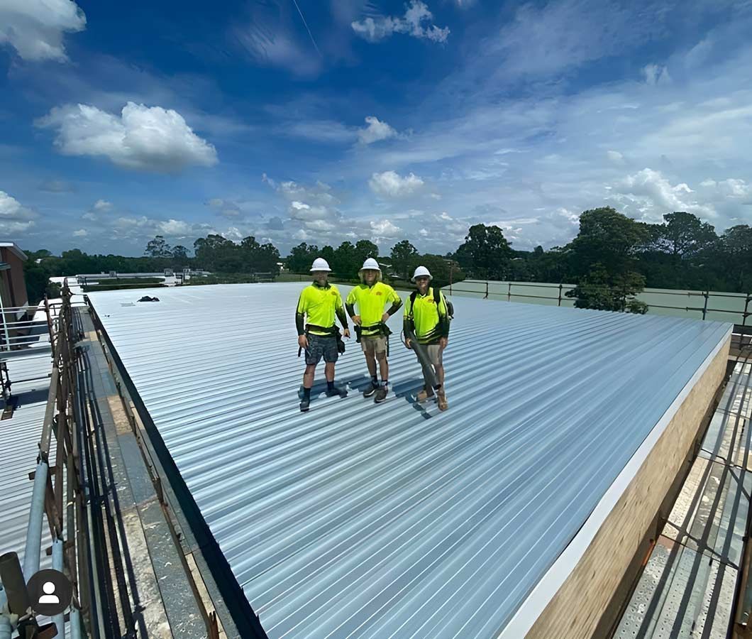 Three Construction Workers Are Standing on Top of a Roof — Ben McLennan Constructions in Grafton, NSW
