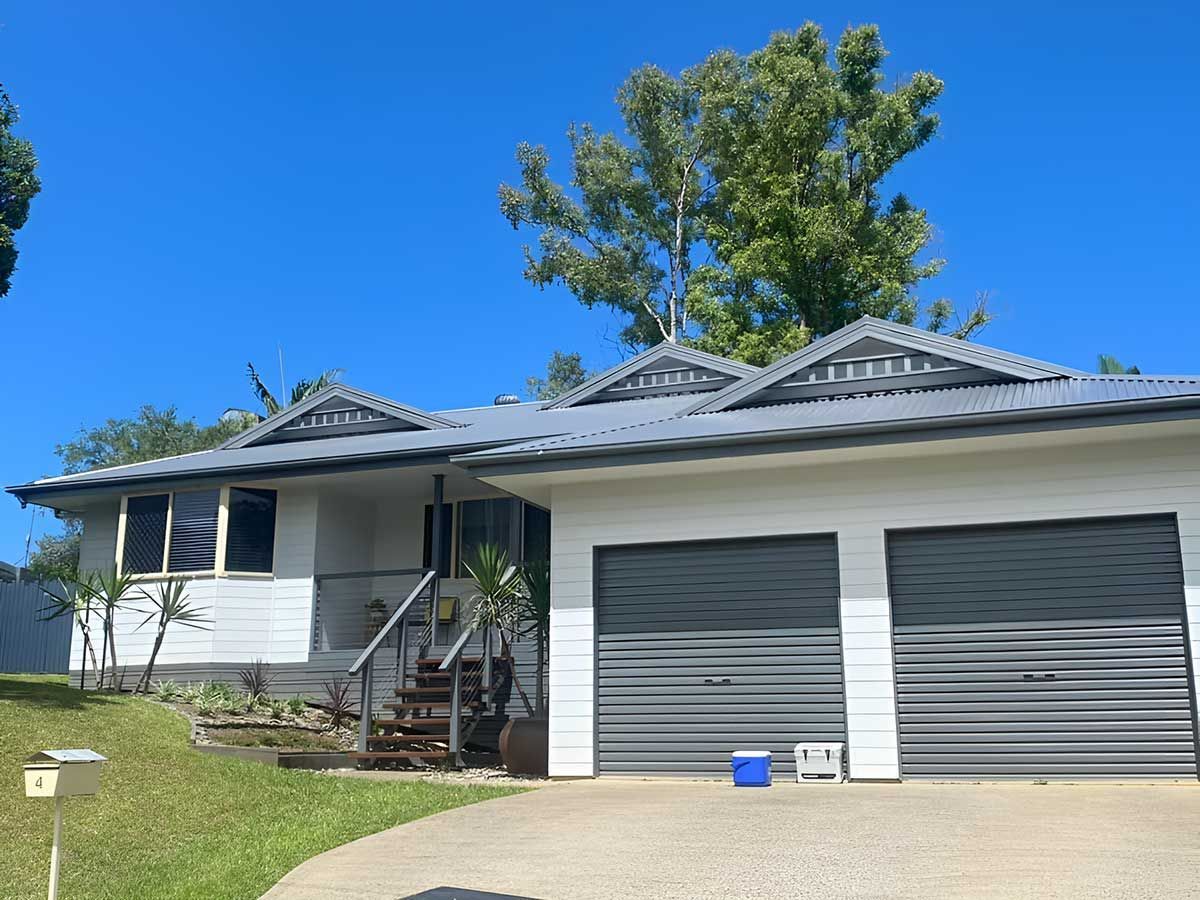 A White House With Two Garage Doors and a Blue Bucket in Front of It — Ben McLennan Constructions in Lismore, NSW