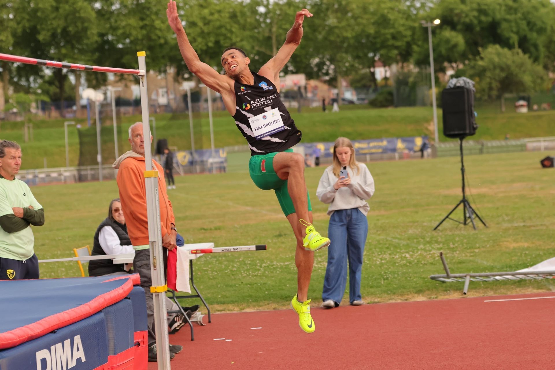 Un sauteur en hauteur franchit la barre lors d'une compétition d'athlétisme en plein air. Saad Hammouda. 