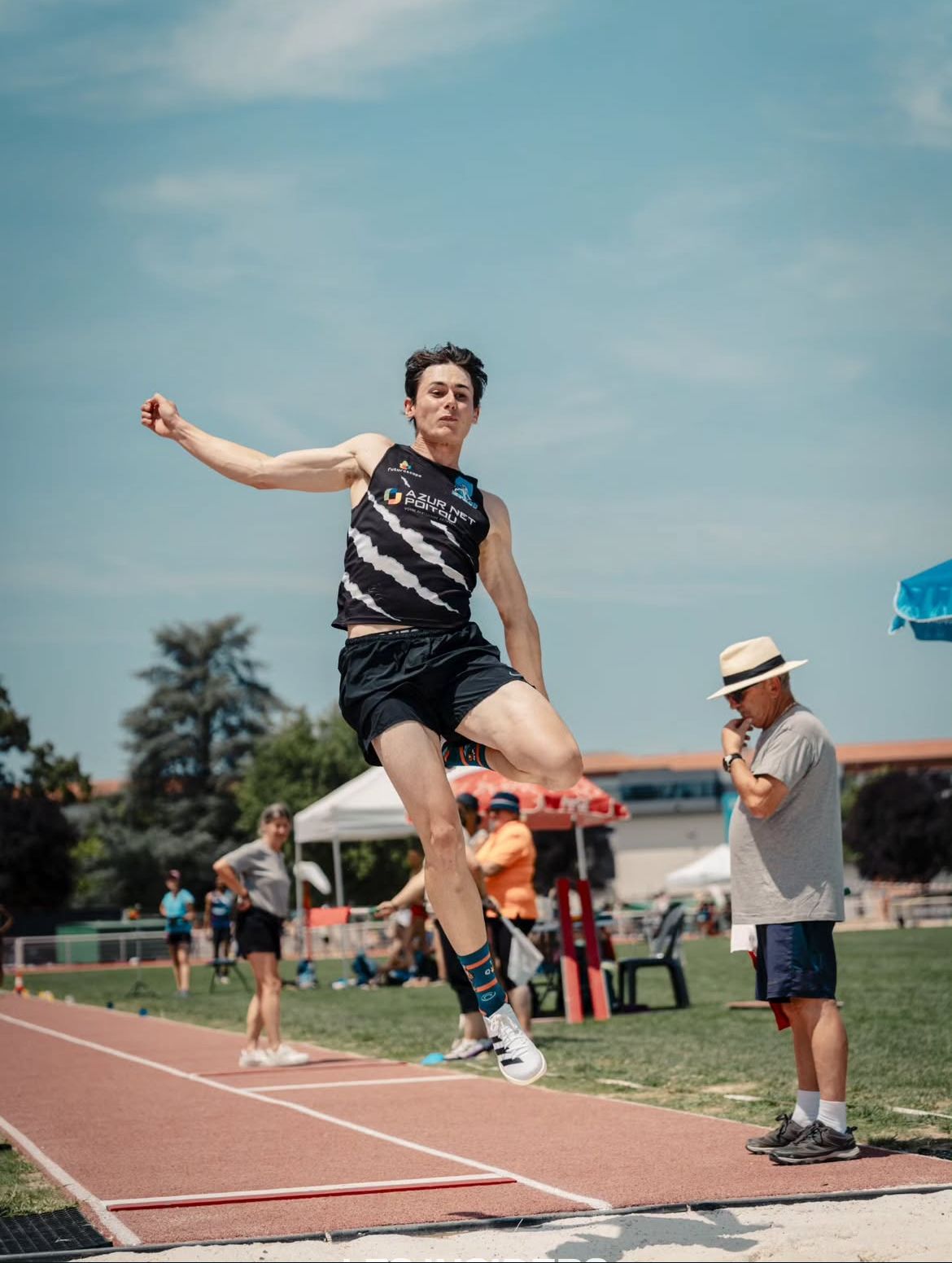 Un athlète masculin saute lors d'une compétition de saut en longueur sur une piste Alistair Piot. 