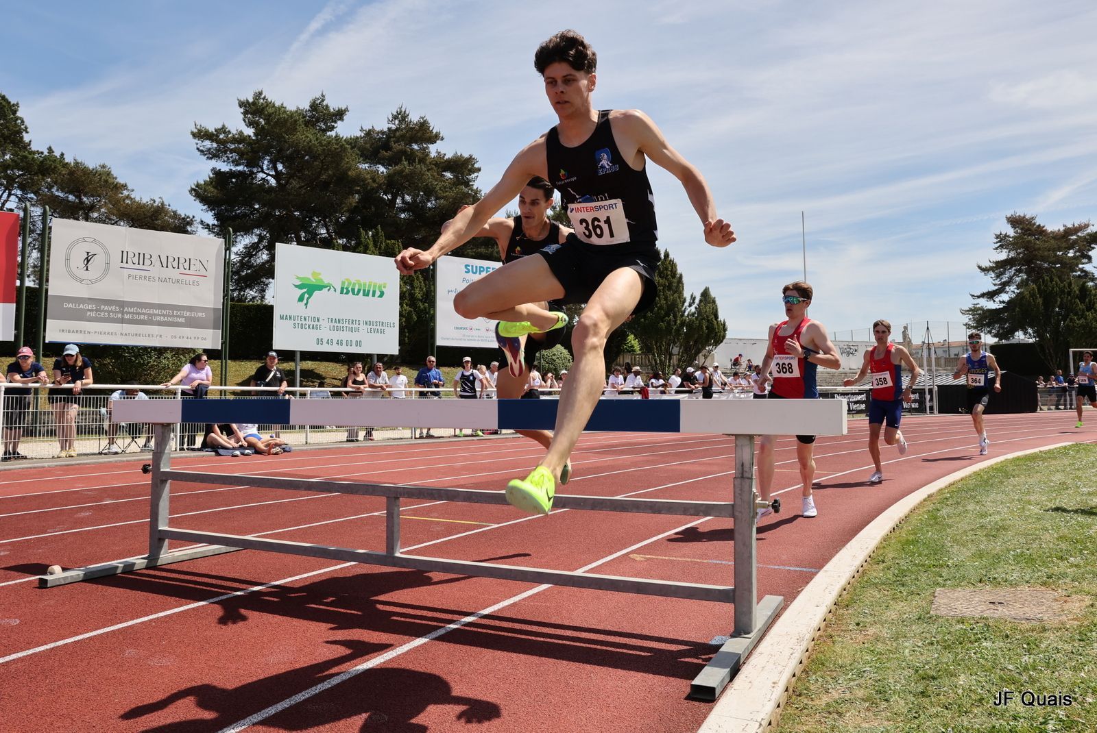 Un athlète, dossard 21, saute une haie sur une piste. Maxime Guyon.