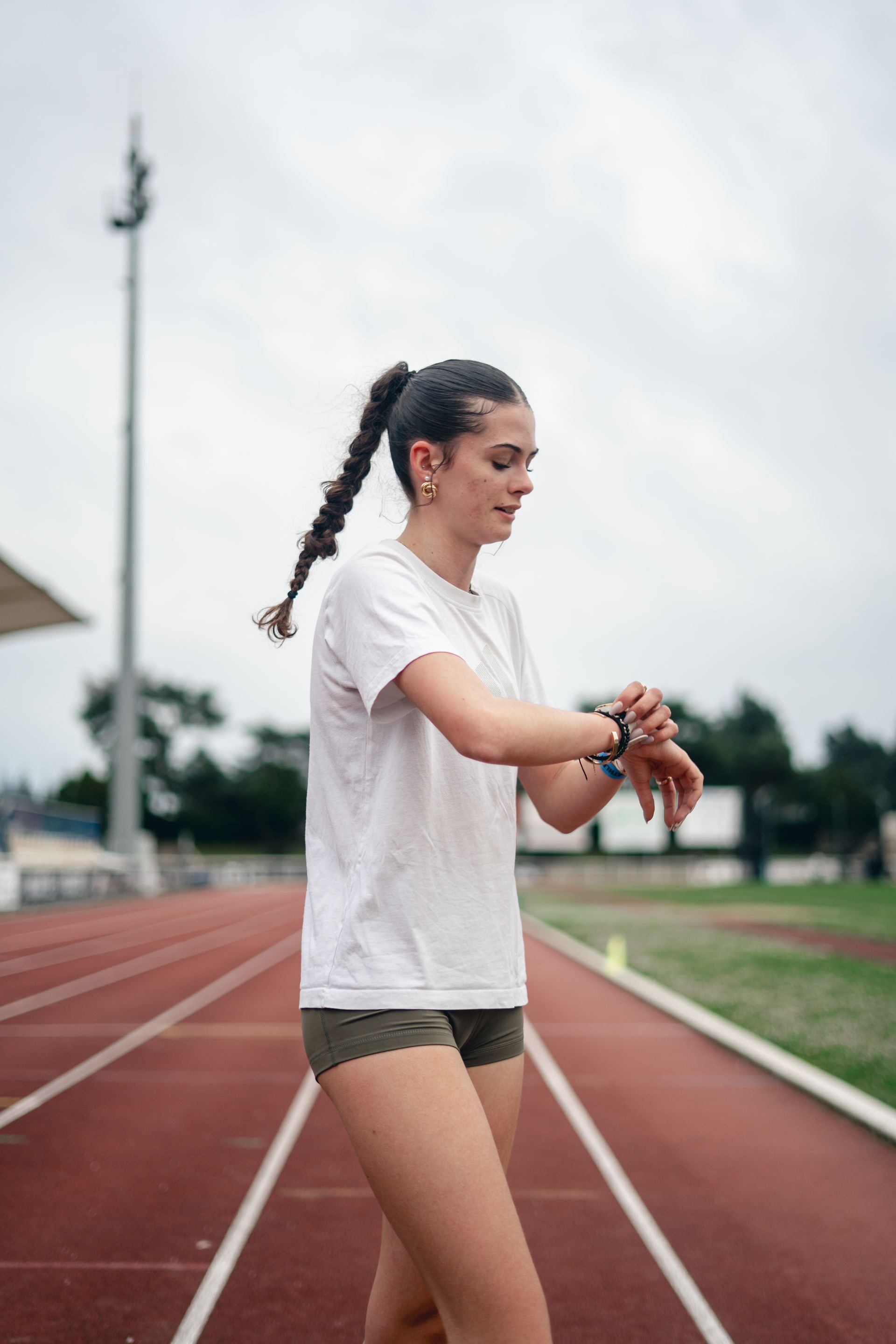 Olivia Martin demi-fondeuse à l'entraînement en tenue de sport sur une piste, regardant sa montre.