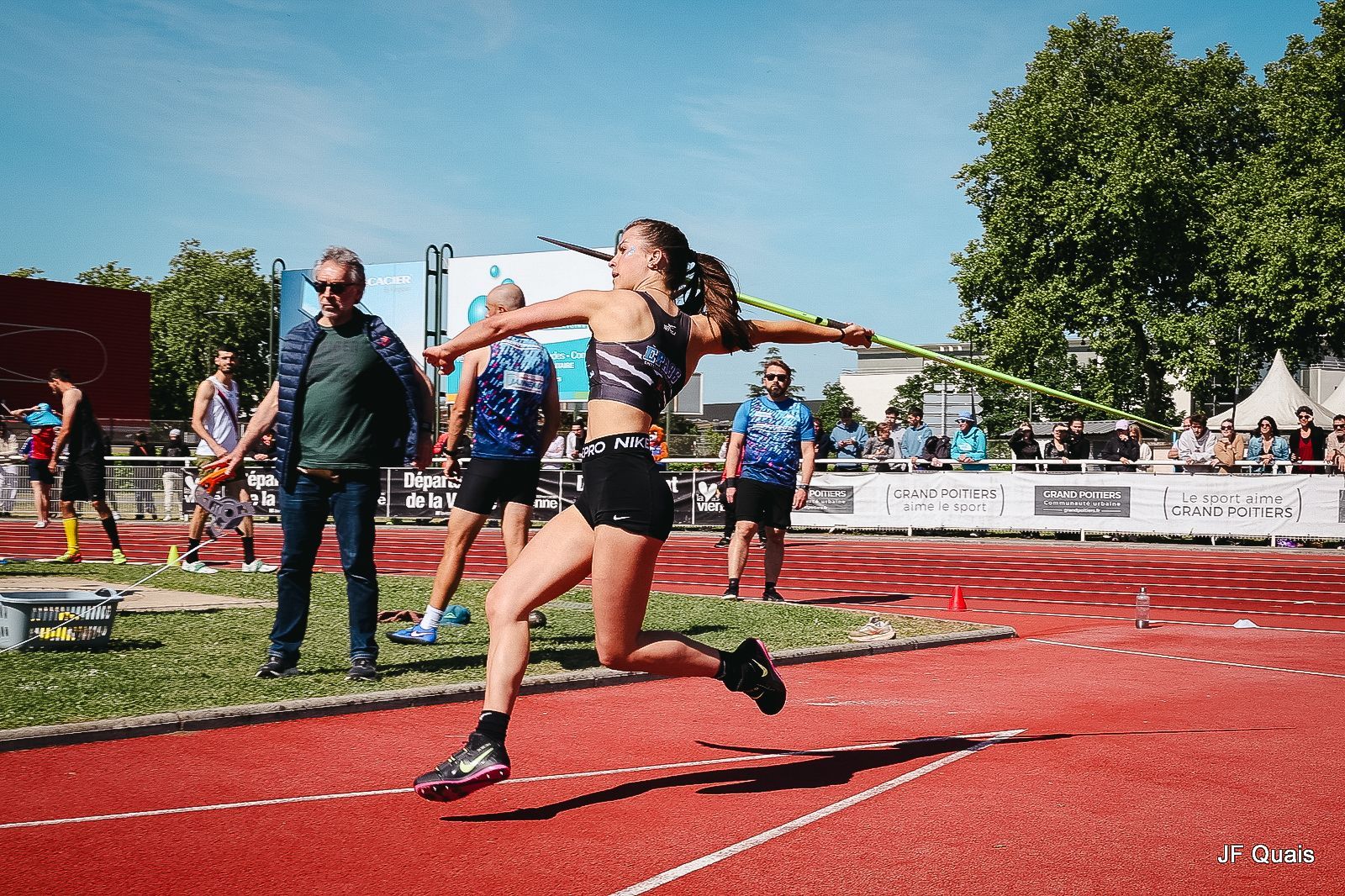 Athlète féminine lançant un javelot dans les airs sur une piste, journée ensoleillée. Anaïs Bossard.