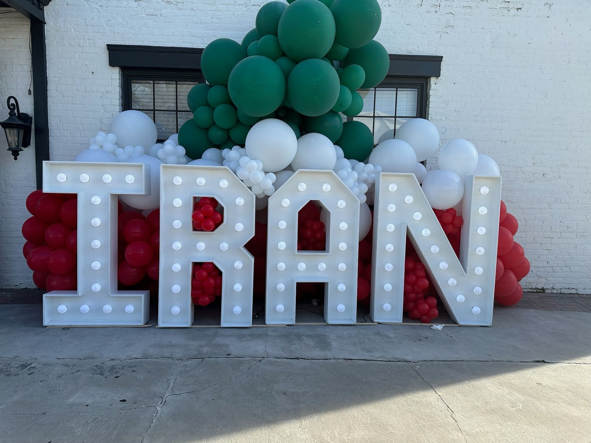 The word iran is surrounded by red white and green balloons