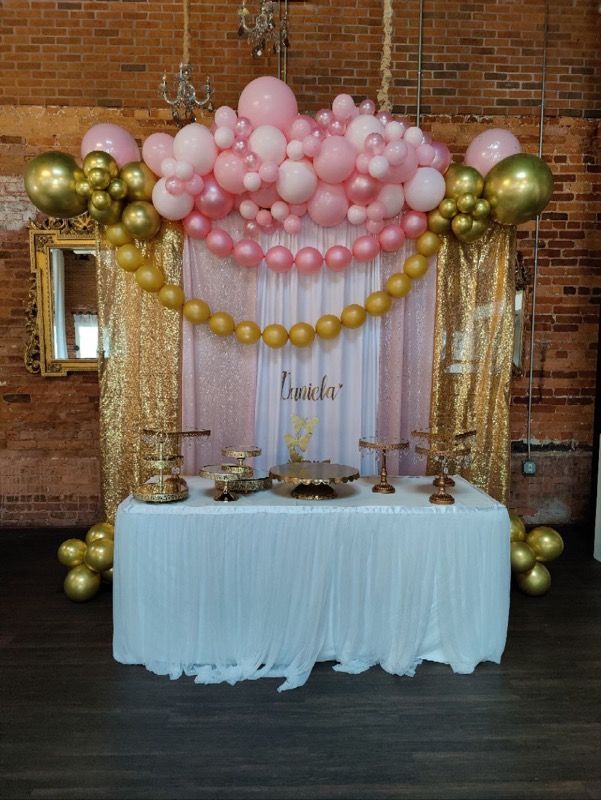 A table is decorated with pink and gold balloons.