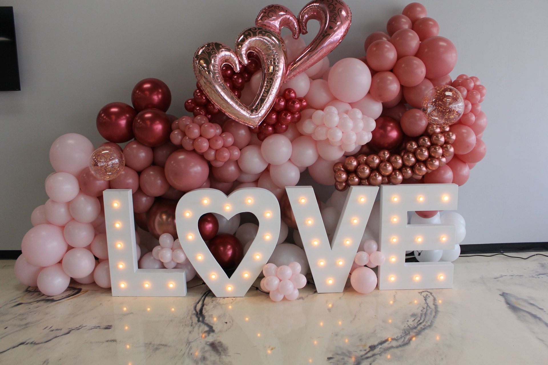 The word love is surrounded by pink and red balloons.