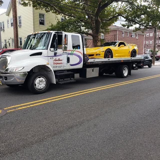 A tow truck with a yellow sports car on the back