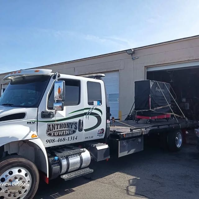 Anthony 's towing truck is parked in front of a garage.