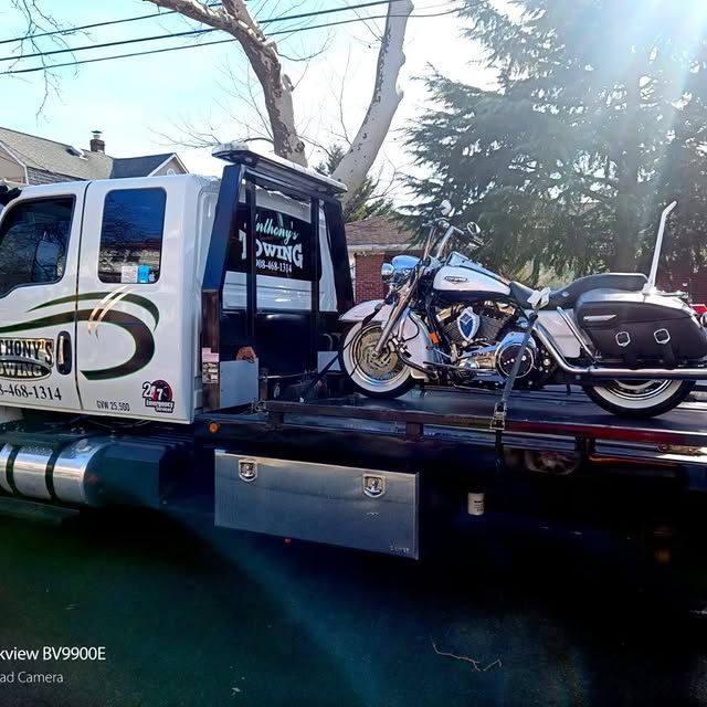 A motorcycle is sitting on the back of a tow truck.