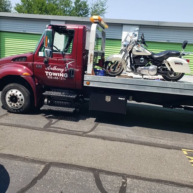 A red towing truck with a motorcycle on the back