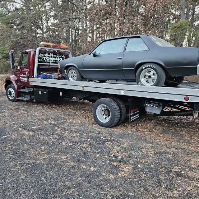 A black car is sitting on top of a tow truck.