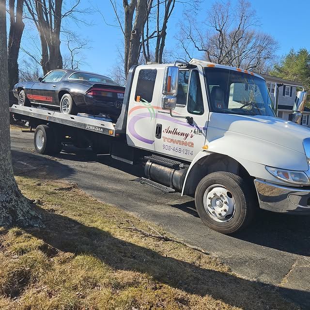A tow truck with a car on the back is parked on the side of the road