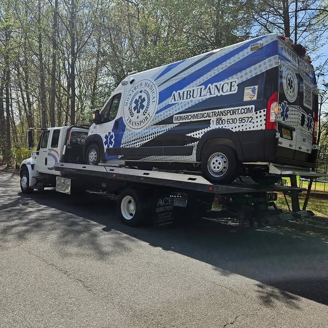 An ambulance is being towed by a tow truck