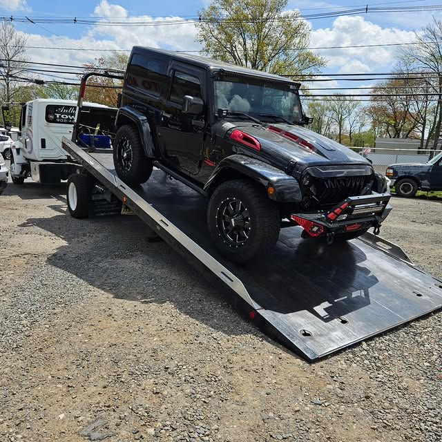 A black jeep is being towed by a tow truck