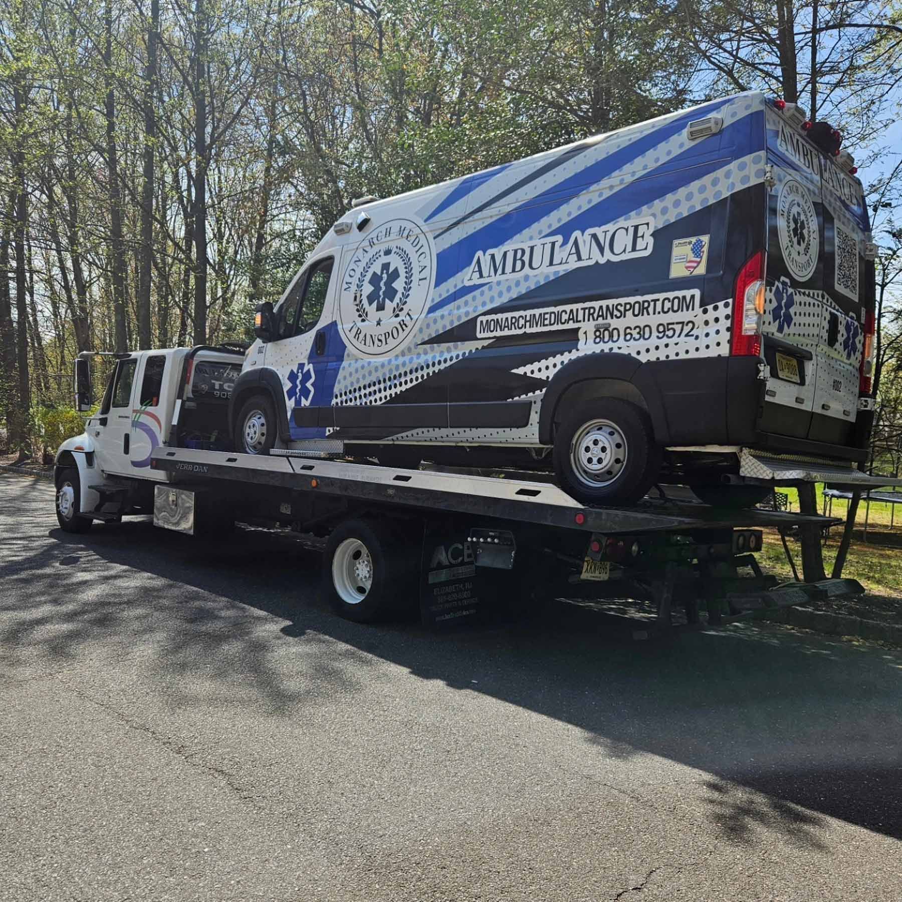 An ambulance is being towed by a tow truck.