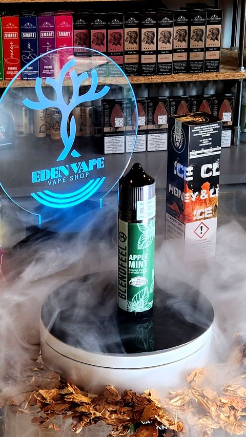 Una boccetta di e-liquid è appoggiata su un tavolo e da essa esce del fumo.
