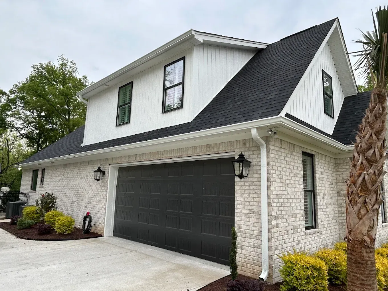 White brick house with black garage door and roof.