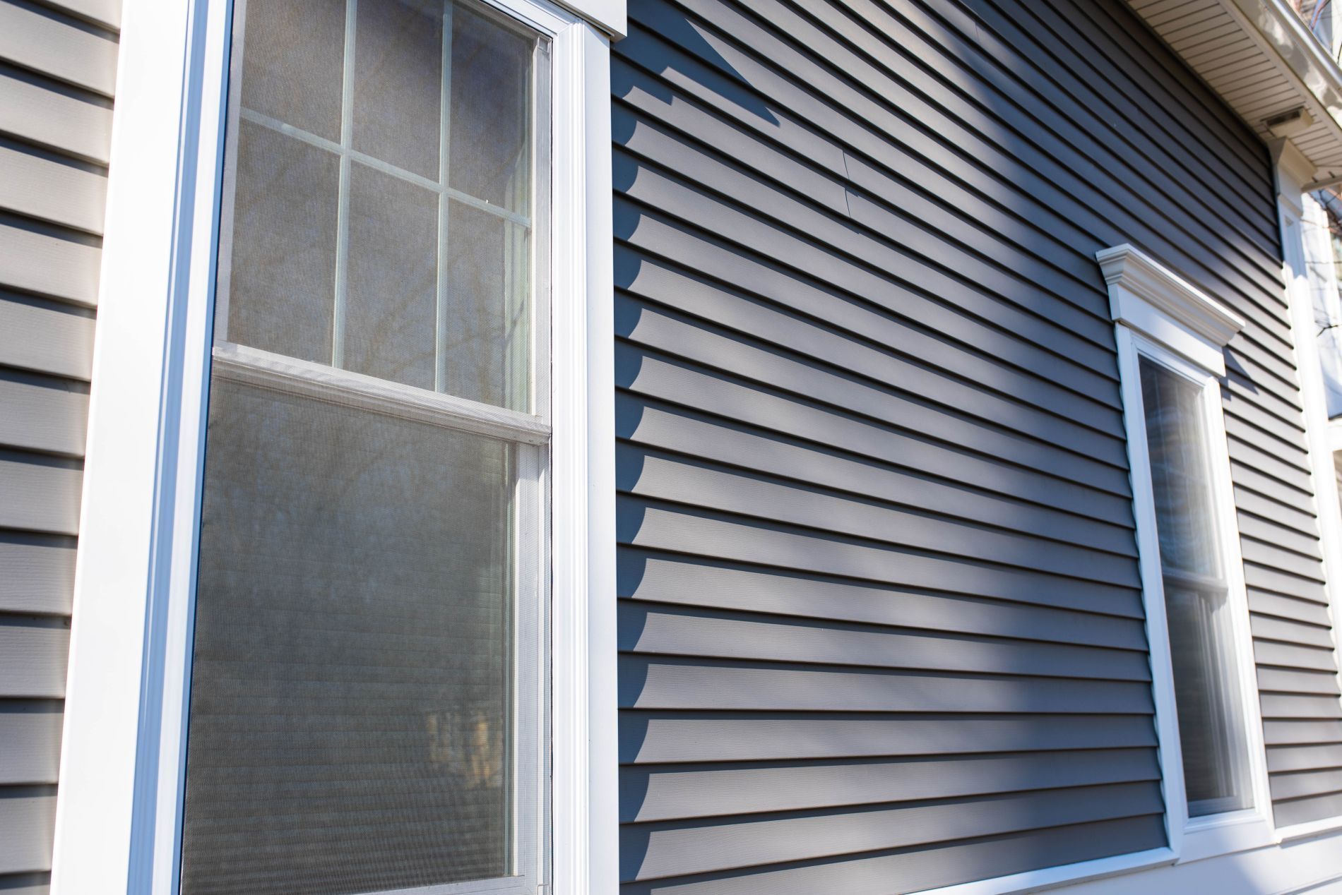 Gray house siding with white trim around windows.