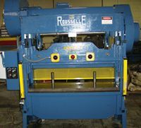 A blue machine is sitting on the floor in a factory.